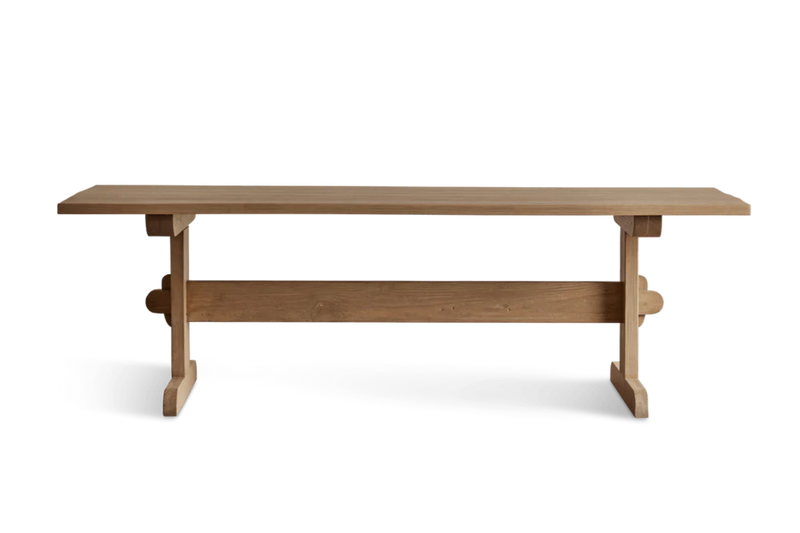 A large, light wooden table with a natural finish, supported by a sturdy central support and curved feet, ideal for dining or meetings.