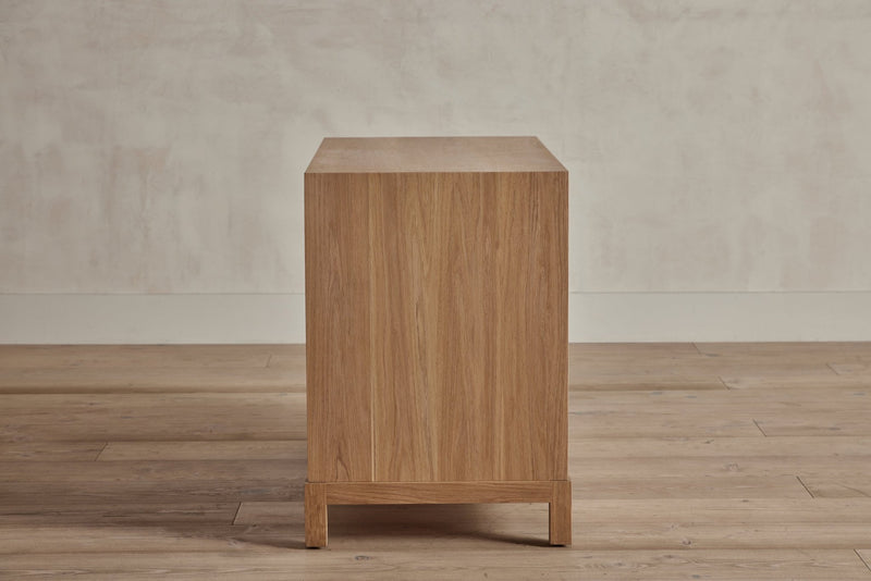 Side view of a wooden 3-drawer chest showing plinth legs and smooth finish.