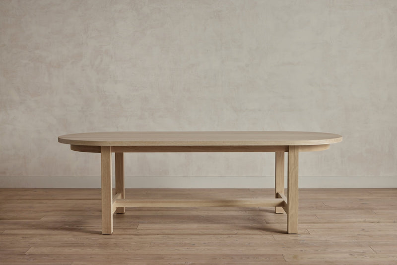 Full view of a wooden table with a rectangular top and four legs, in a room with wooden floor.